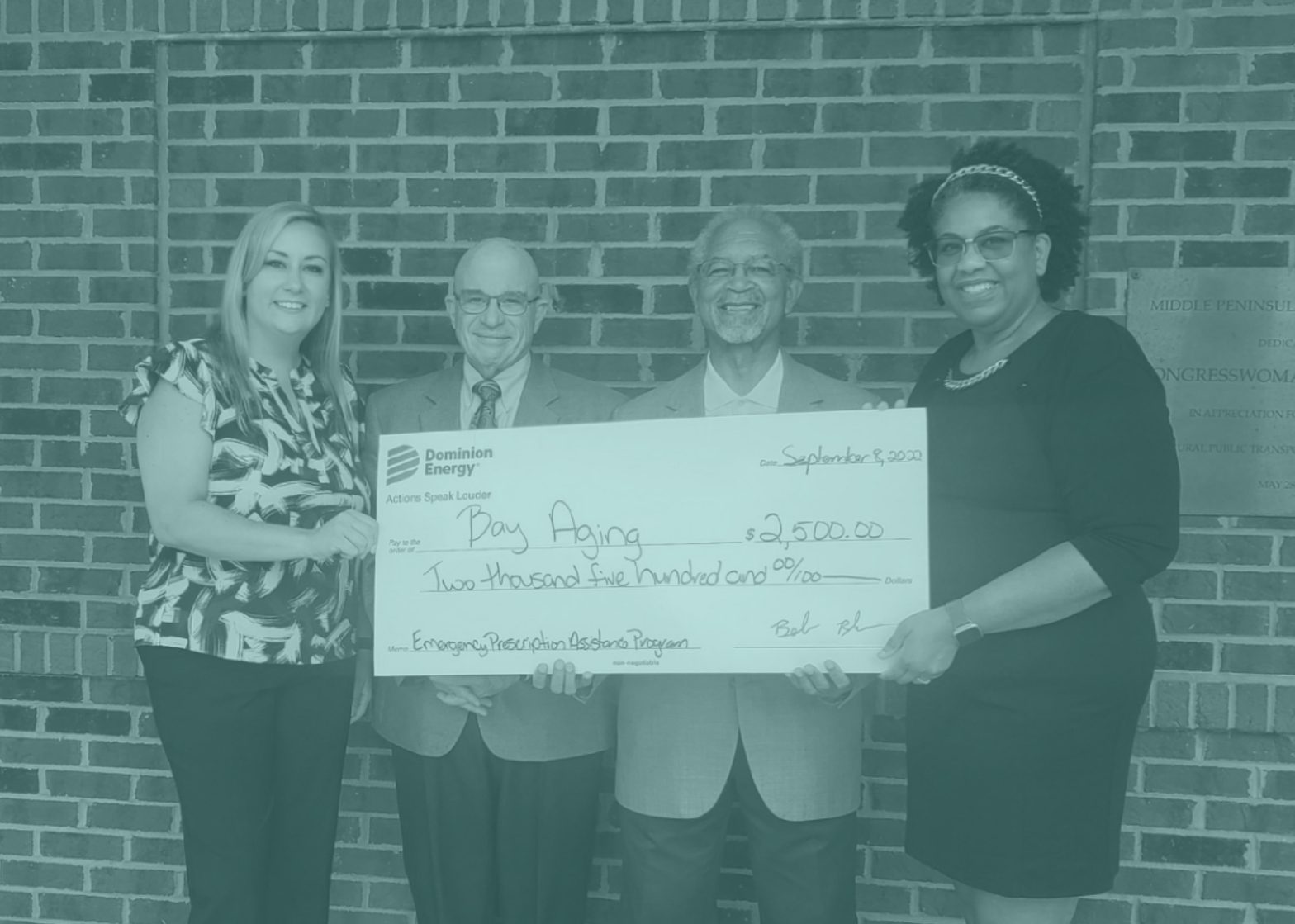Four people holding large check