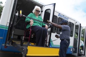 woman in wheelchair being lowered from bus