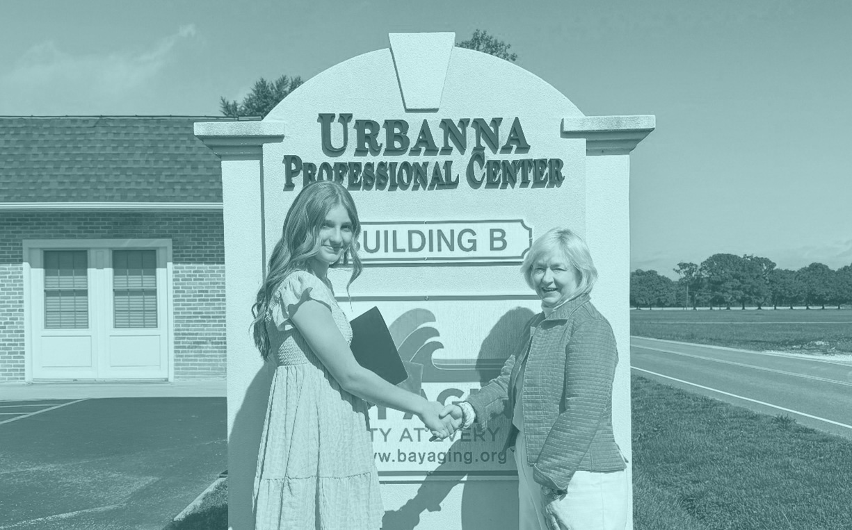 Two women Shaking hands in front of sign
