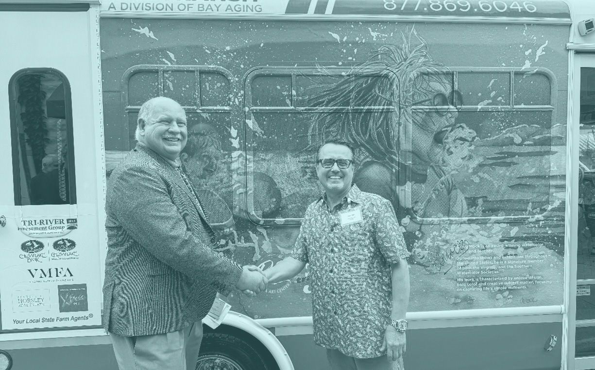Two men shaking hands in front of bus with mural