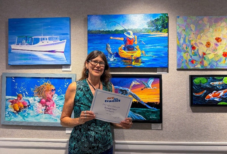 Woman standing in front of wall of paintings holding award