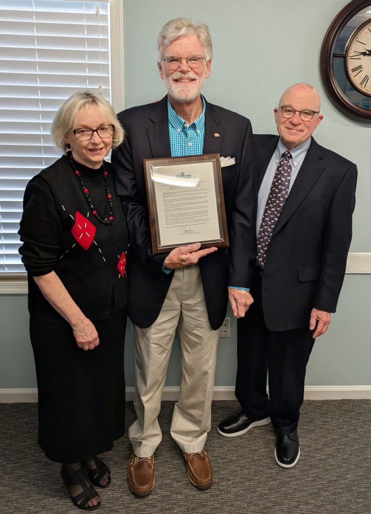 Three people, one holding award