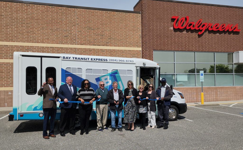 People holding ribbon standing in front of bus