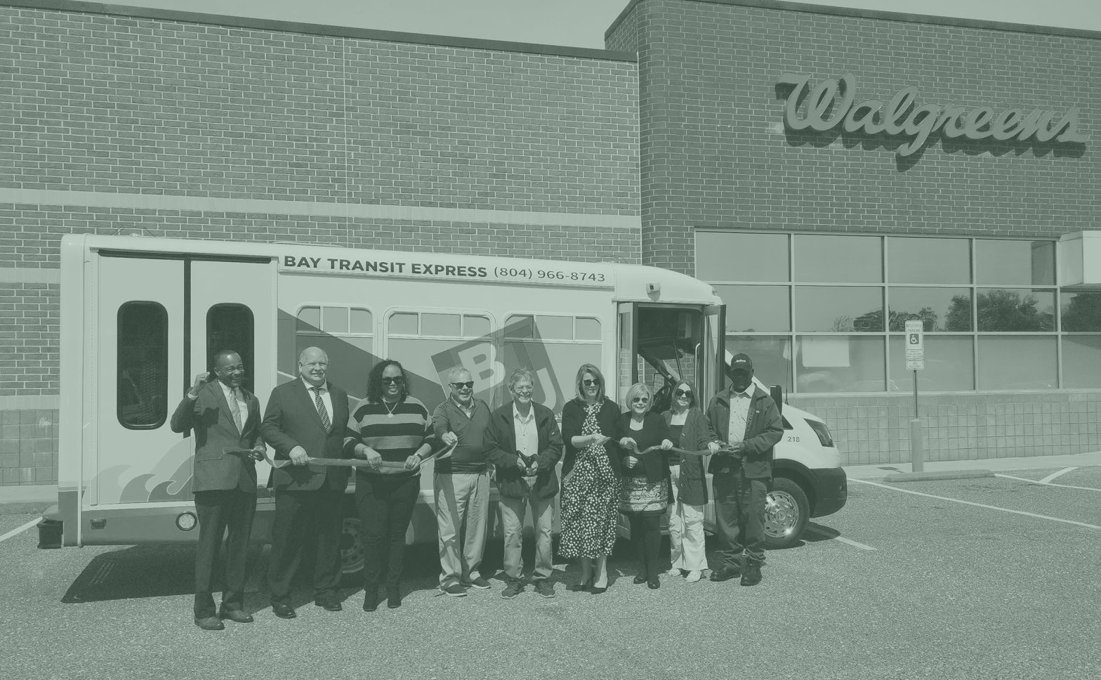 People holding ribbon standing in front of bus