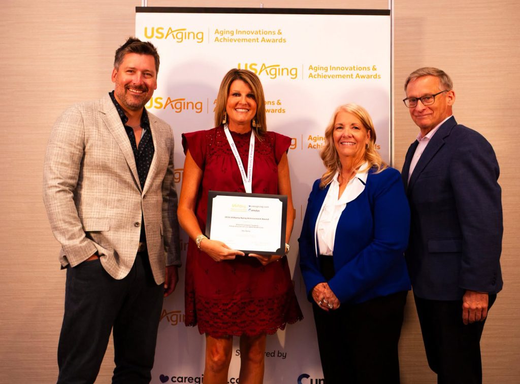 Four people holing award in front of banner